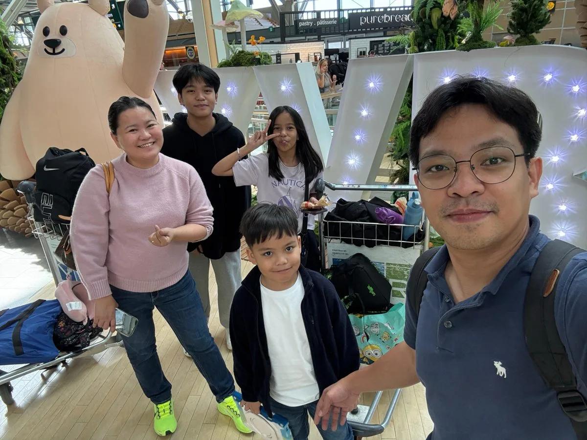 Peter taking a photo with his family at an airport in Vancouver